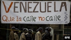 Un grupo de manifestantes se defienden de la policía durante una protesta